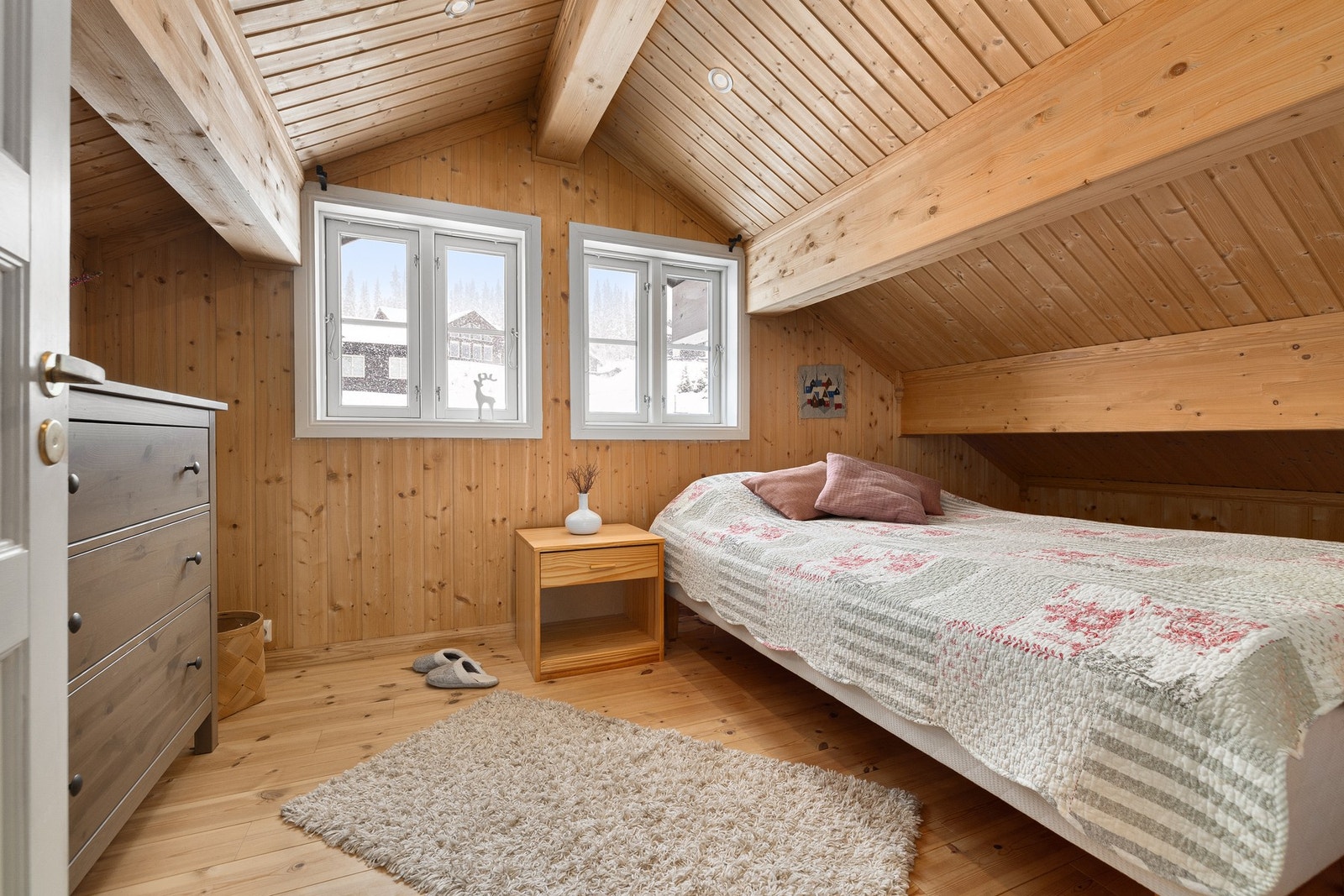 Sjarmerende soverom med skråtak og lune tømmervegger. Galleribilde