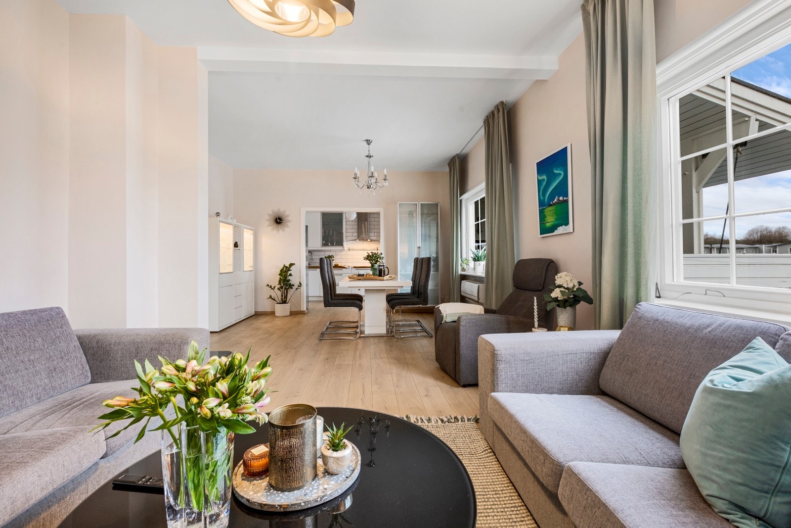 Lys og trivelig stue som er delt opp i dagligstue og spisestue Galleribilde