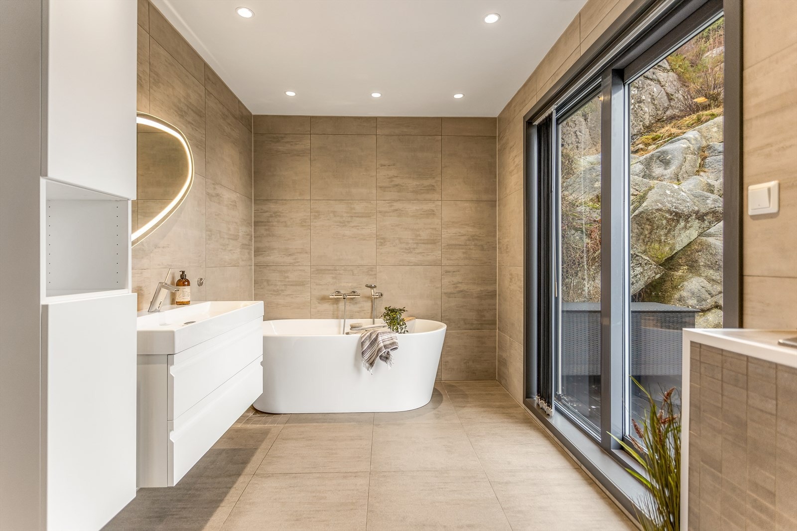 Badet er nydelig innredet med store fliser på gulv og vegger, samt flott og moderne badekar Galleribilde