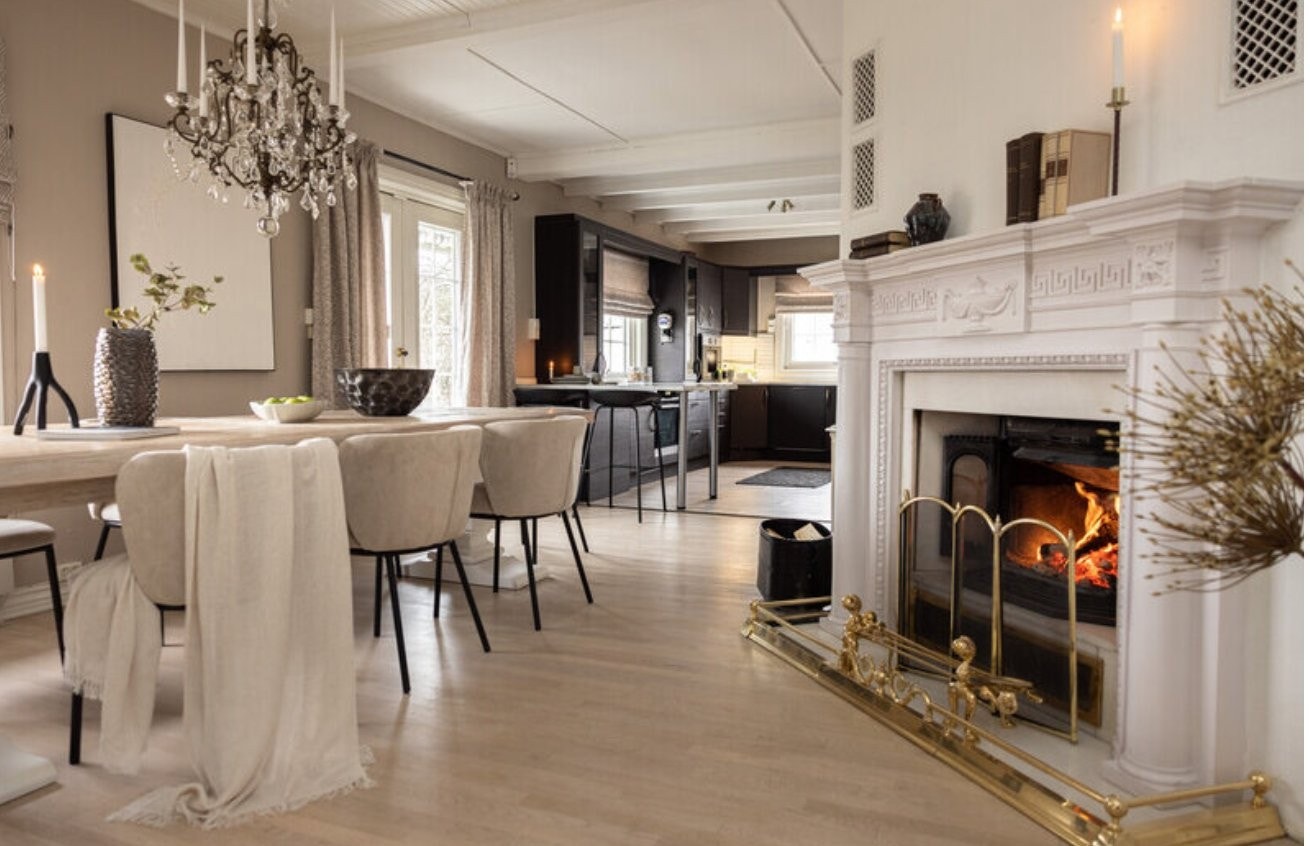 Fra stuen mot kjøkken og Jøtul 18-peis. Mindre vedovn ved kjøkkenøyen – praktisk også for koking ved behov. Galleribilde