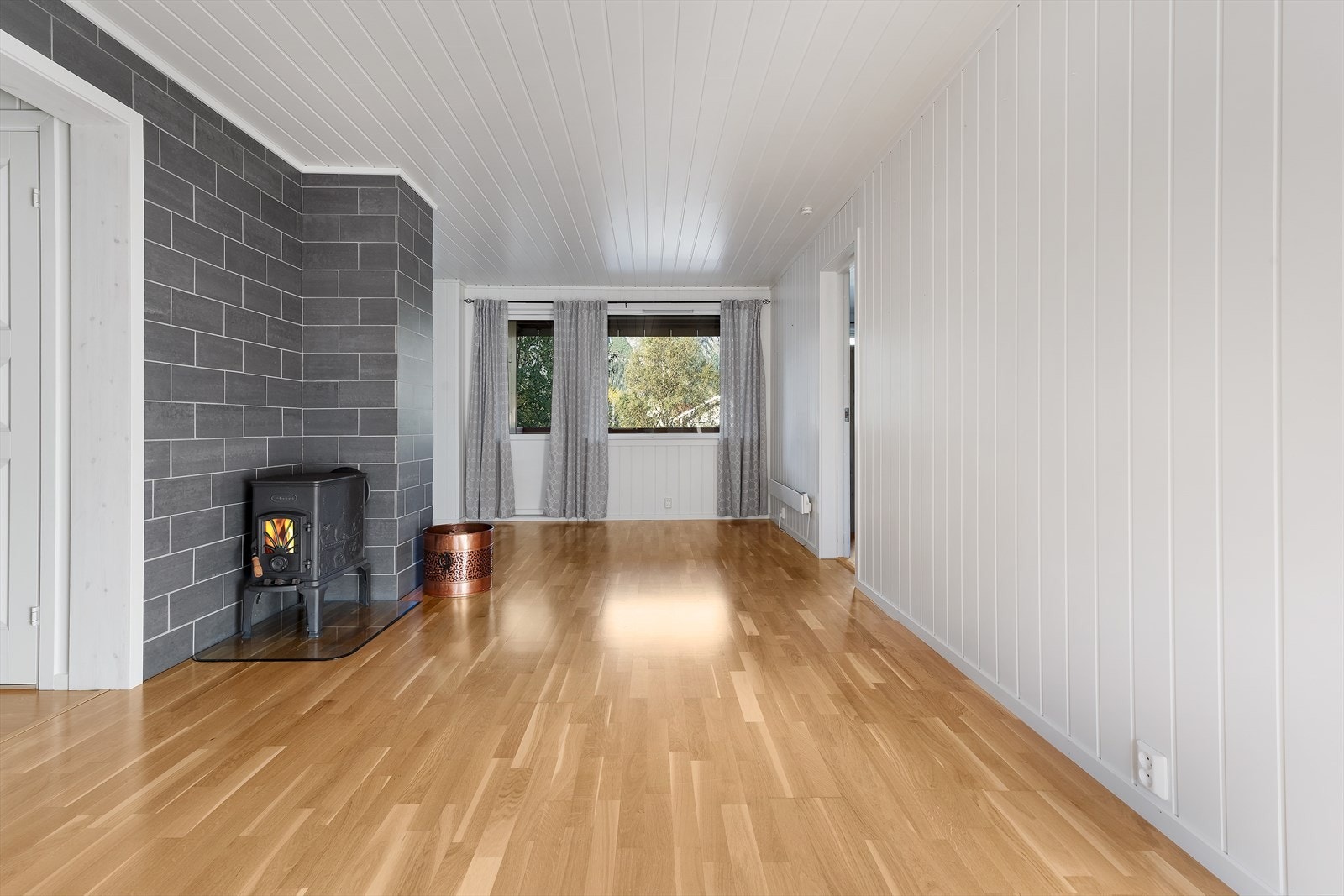 Fra kjøkkendel mot stue. Koselig med vedovn. I dette området er det naturlig å plassere spisebord og kanskje en liten sittegruppe. Videre ser du dør ut til veranda. Galleribilde