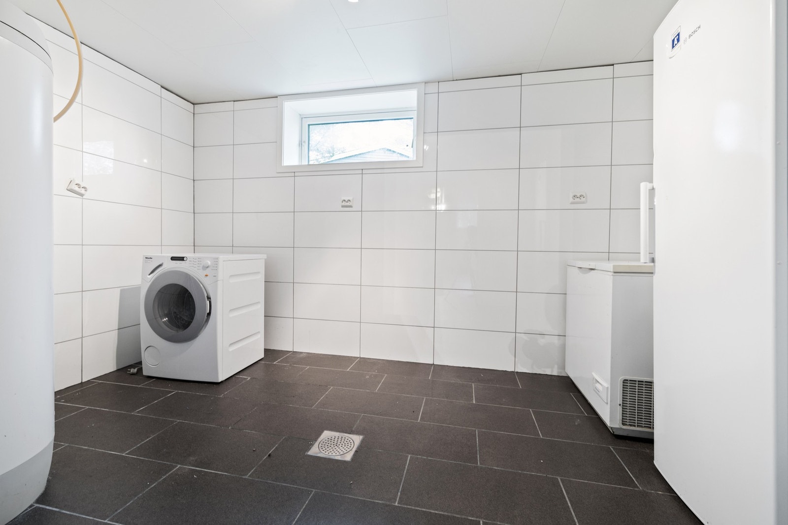 Vaskerom i kjeller. Opplegg for vaskemaskin. Varmtvannsbereder. Galleribilde