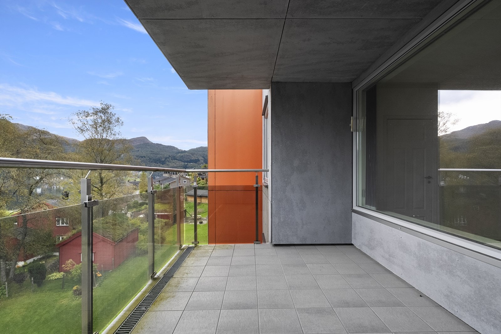 Balkongen har flislagt golv, rekkverk i glass og takoverbygg Galleribilde