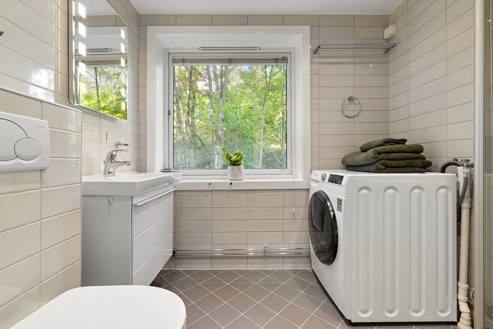 Badet er innredet med vegghengt toalett, vegghengt servant og speil Galleribilde