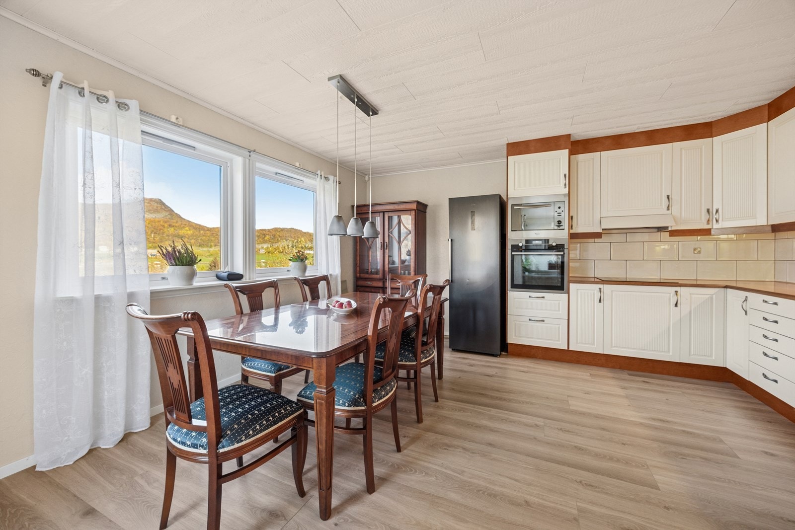 Lyst og tidløst kjøkken med hvite profilerte fronter og benkeplate av typen laminat. Galleribilde