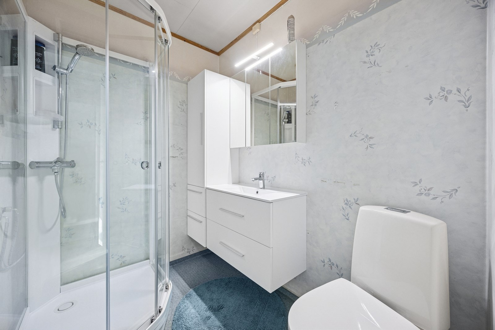 Eldre bad utstyrt med dusjakbinett, gulvstående toalett og moderne baderomsinnredning. Galleribilde