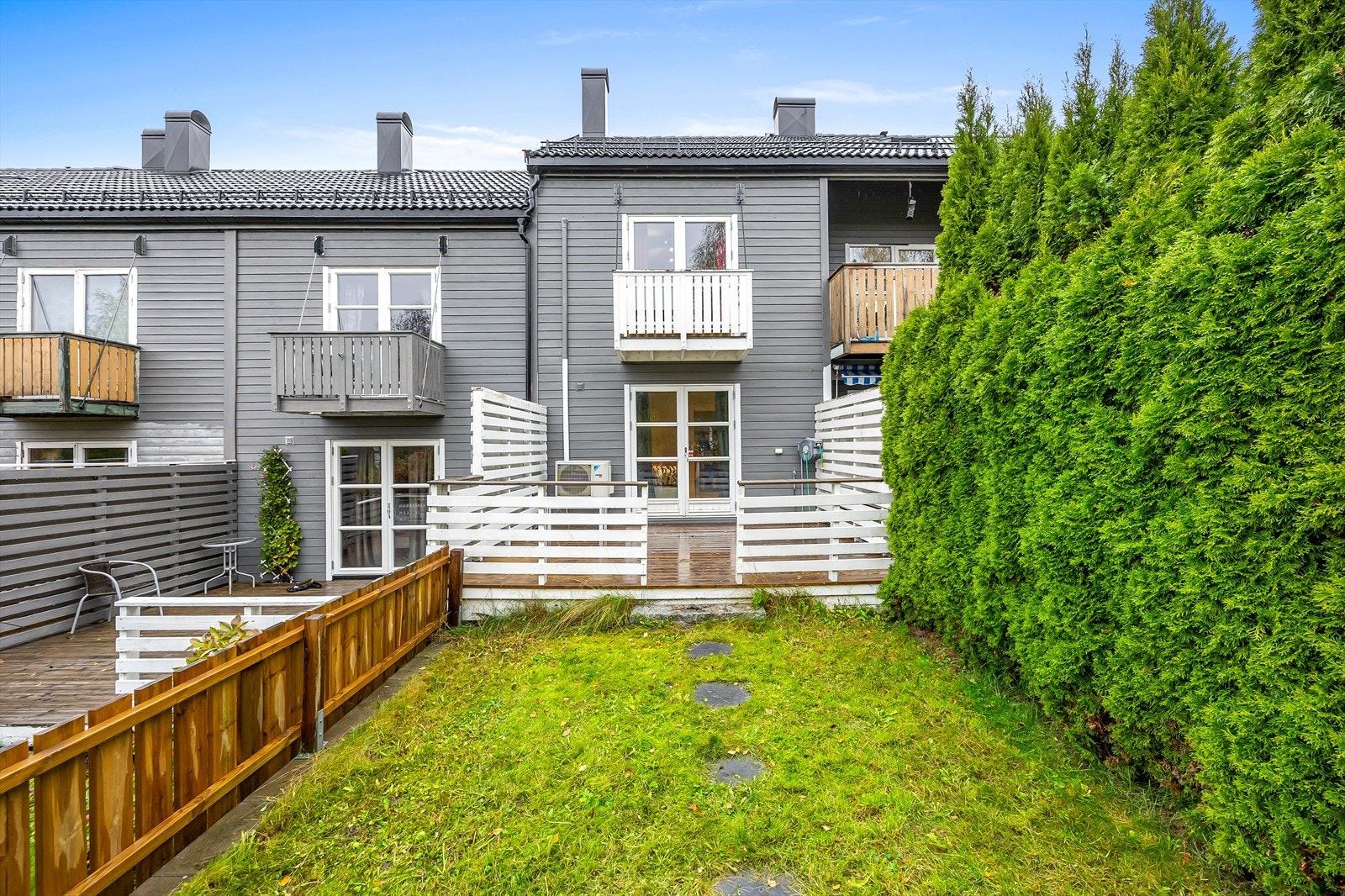 Boligens bakside med hage og flere uteplasser. Taket ble lagt om med ny takstein i 2023. Galleribilde