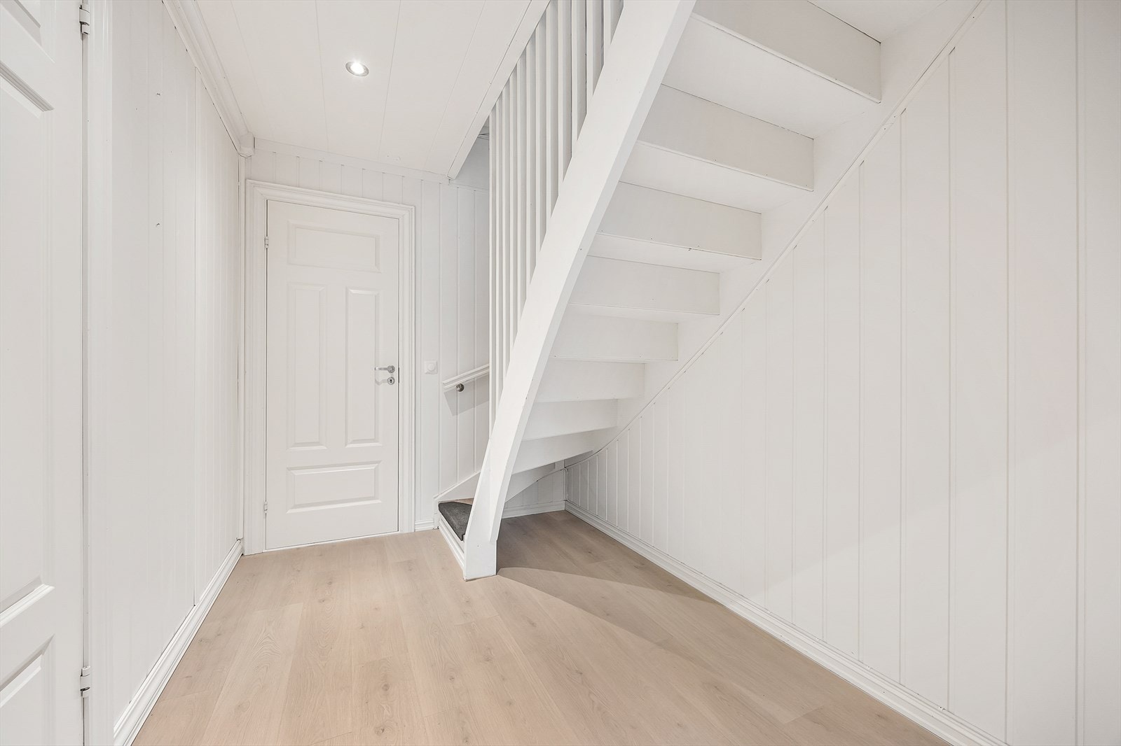 Hvit innvendig trapp som forbinder boligens etasjer. Det er lagt antisklitepper på trappetrinnene. Galleribilde