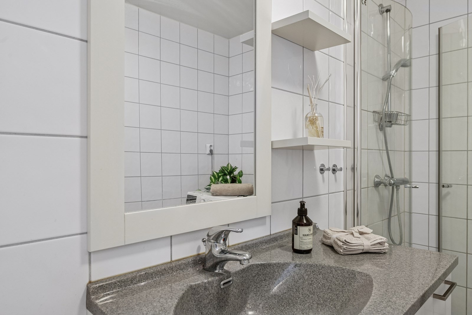 Baderommet er innredet med en nedfelt servant, toalett, dusjvegger/hjørne og opplegg for vaskemaskin. Galleribilde