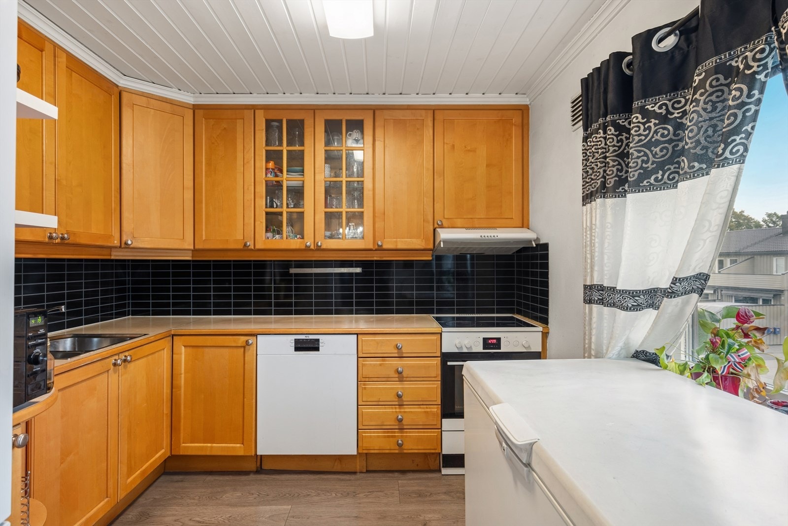 Kjøkkenet er i eget rom med plass til spisebord ved vinduet. Kjøkkeninnredning med profilerte fronter og benkeplate av laminat. Galleribilde