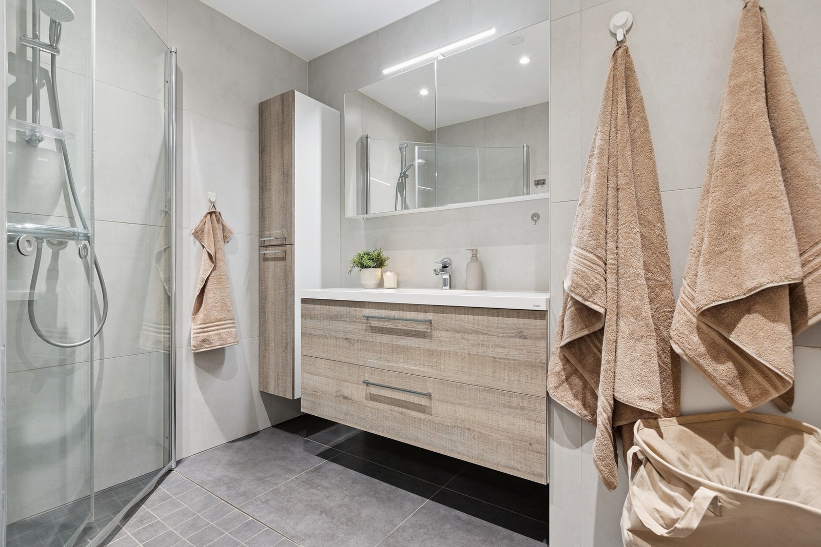 Moderne og lekkert baderom utstyrt med stor servantinnredning, speilskap, vegghengt skap og dusjhjørne. Galleribilde