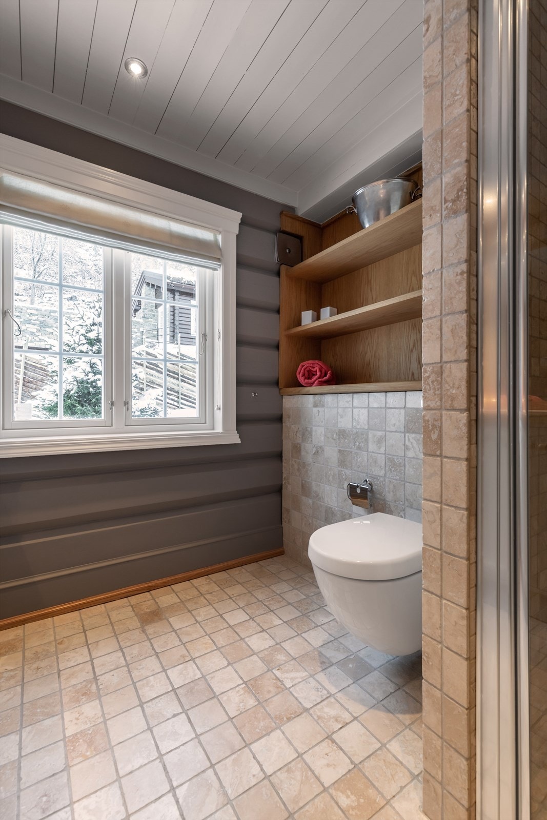 Lyst og hyggelig bad i hovedplan med integrerte hyller i eik, vegghengt toalett, dusjnisje og plassbygd baderomsinnredning Galleribilde