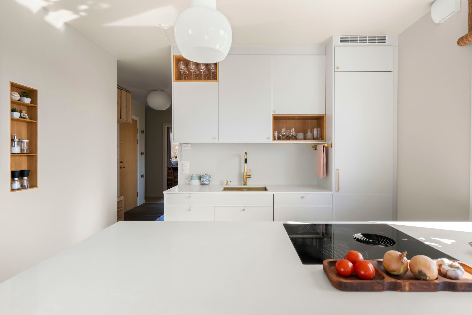 Underlimt vask i gullfarget metall, med blandebatteri fra Tapwell. Integrert i innredningen er komfyr fra AEG, kjøleskap fra Miele, oppvaskmaskin fra Miele, fyskeskap fra Beko, planlimt induksjonstopp med innebygd kullfilter fra BORA Galleribilde