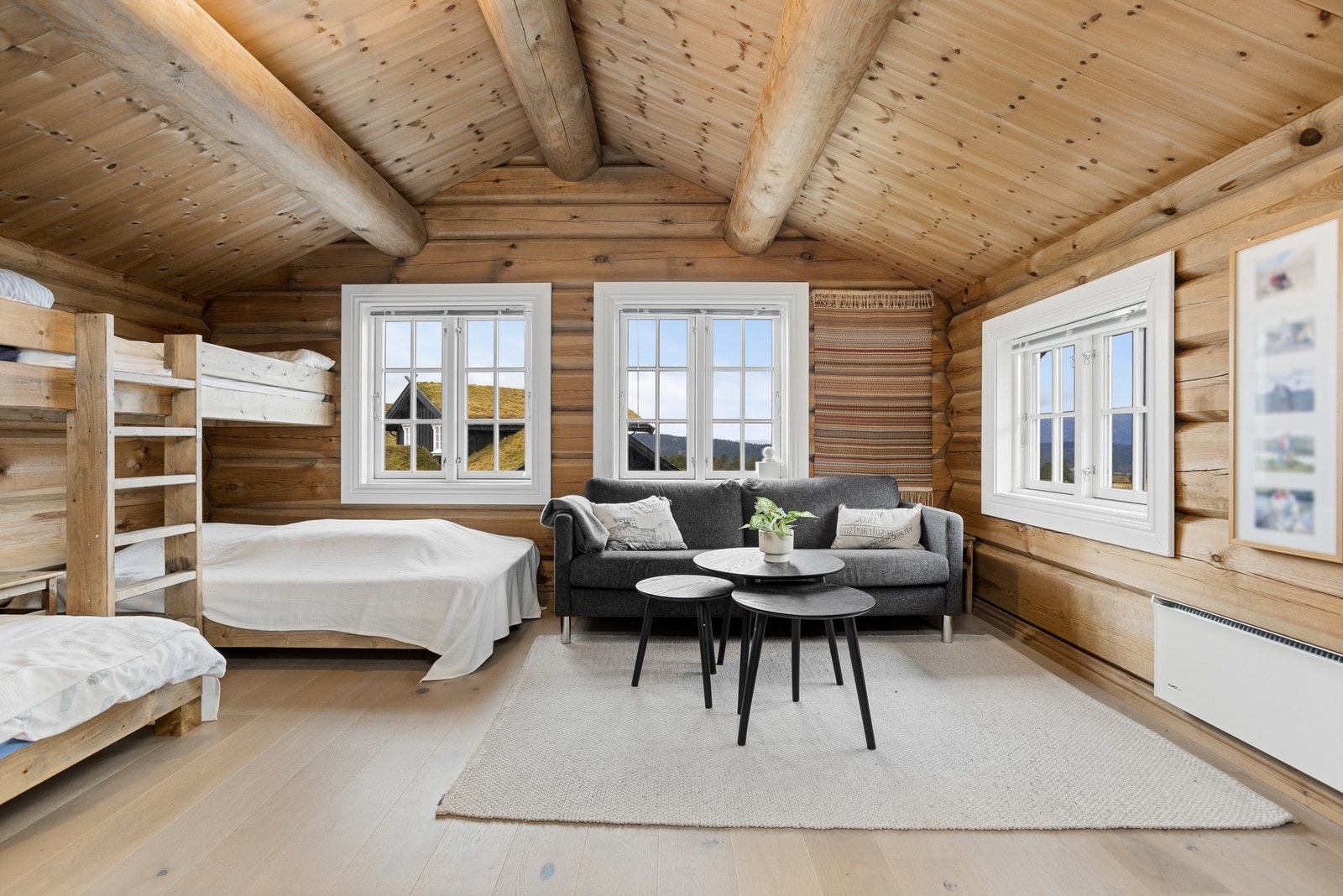 Romslig loftstue innredet med sofagruppe og plassbygde senger Galleribilde