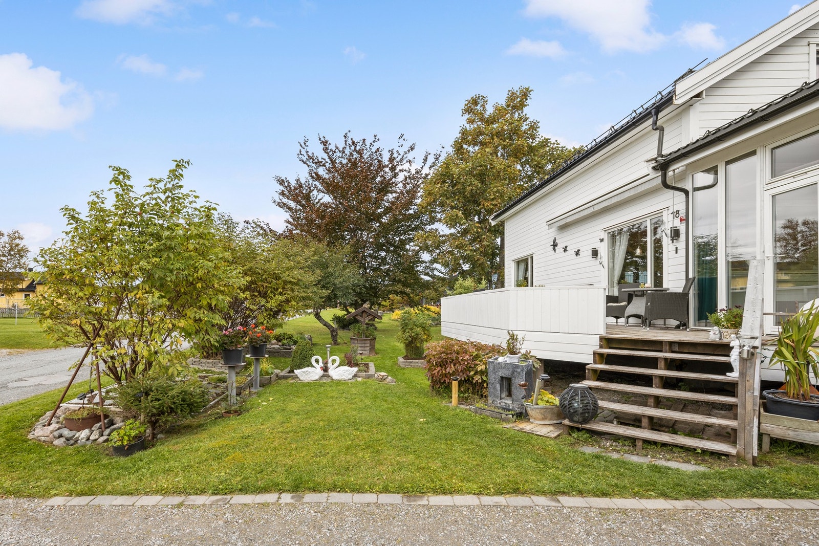 Plenlagt areal som er pent beplantet med blomsterbed, busker og trær Galleribilde