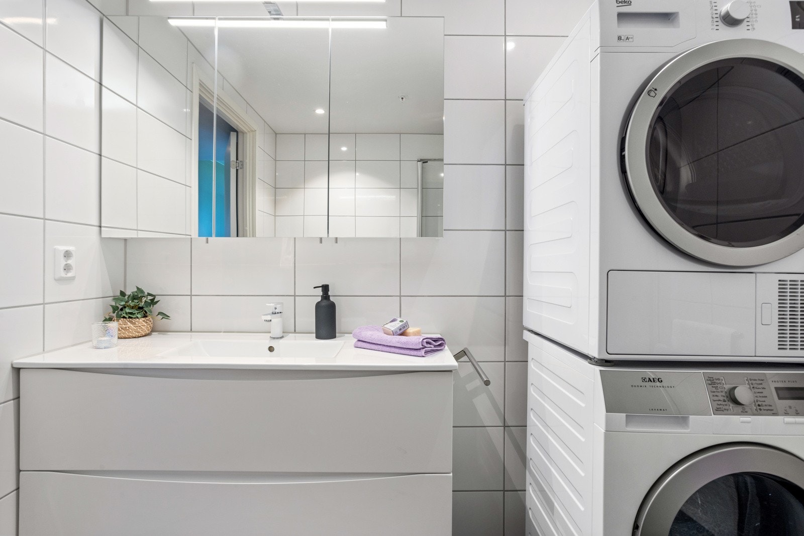 Baderom innredet med vegghengt servantinnredning med skuffer, speilskap med overlys. Dusjhjørne med glassdører. Opplegg for vaskemaskin Galleribilde