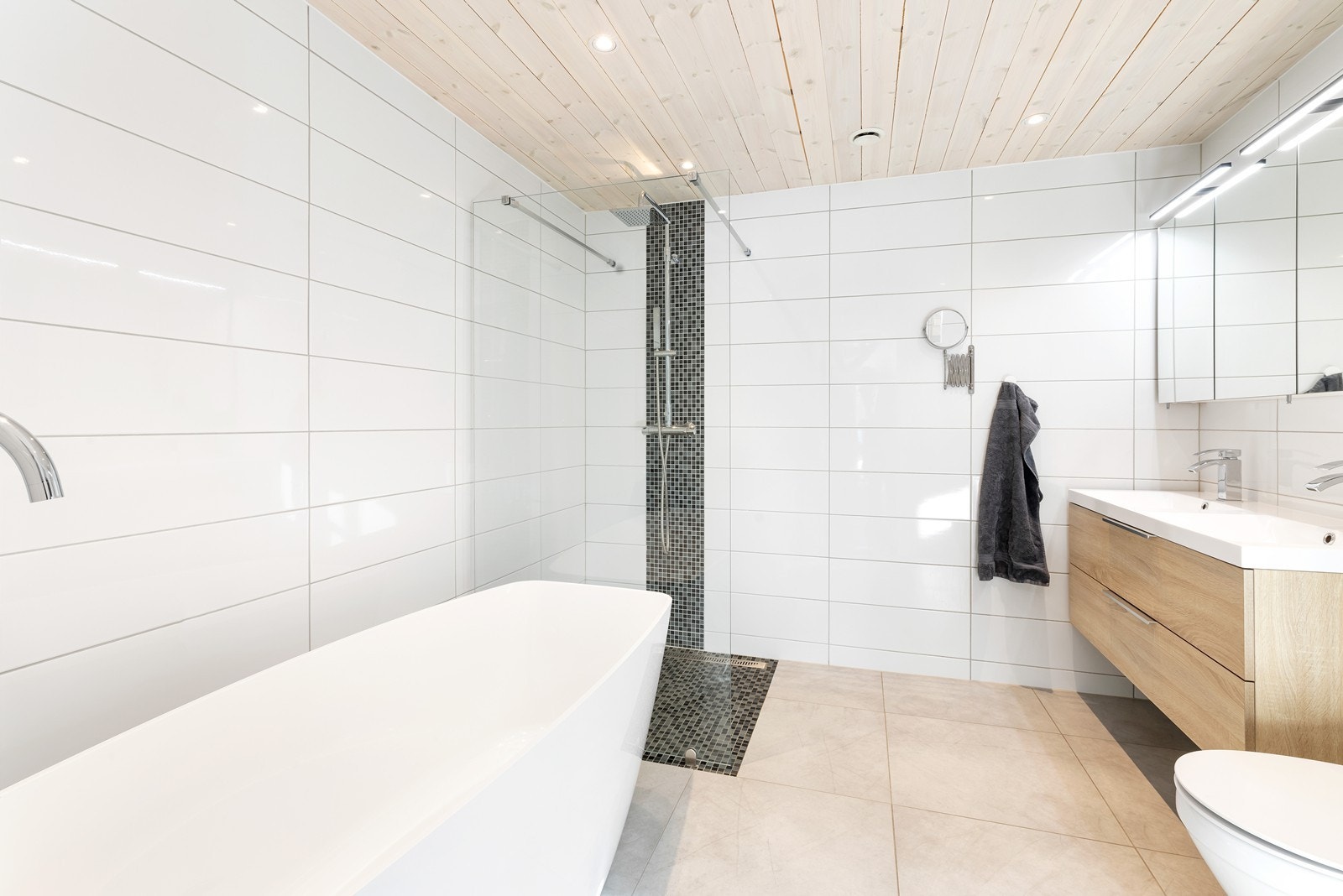 Pent flislagt bad med varmekabler i gulv. Inneholder dusjhjørne, dobbelservant, wc og badekar. Galleribilde