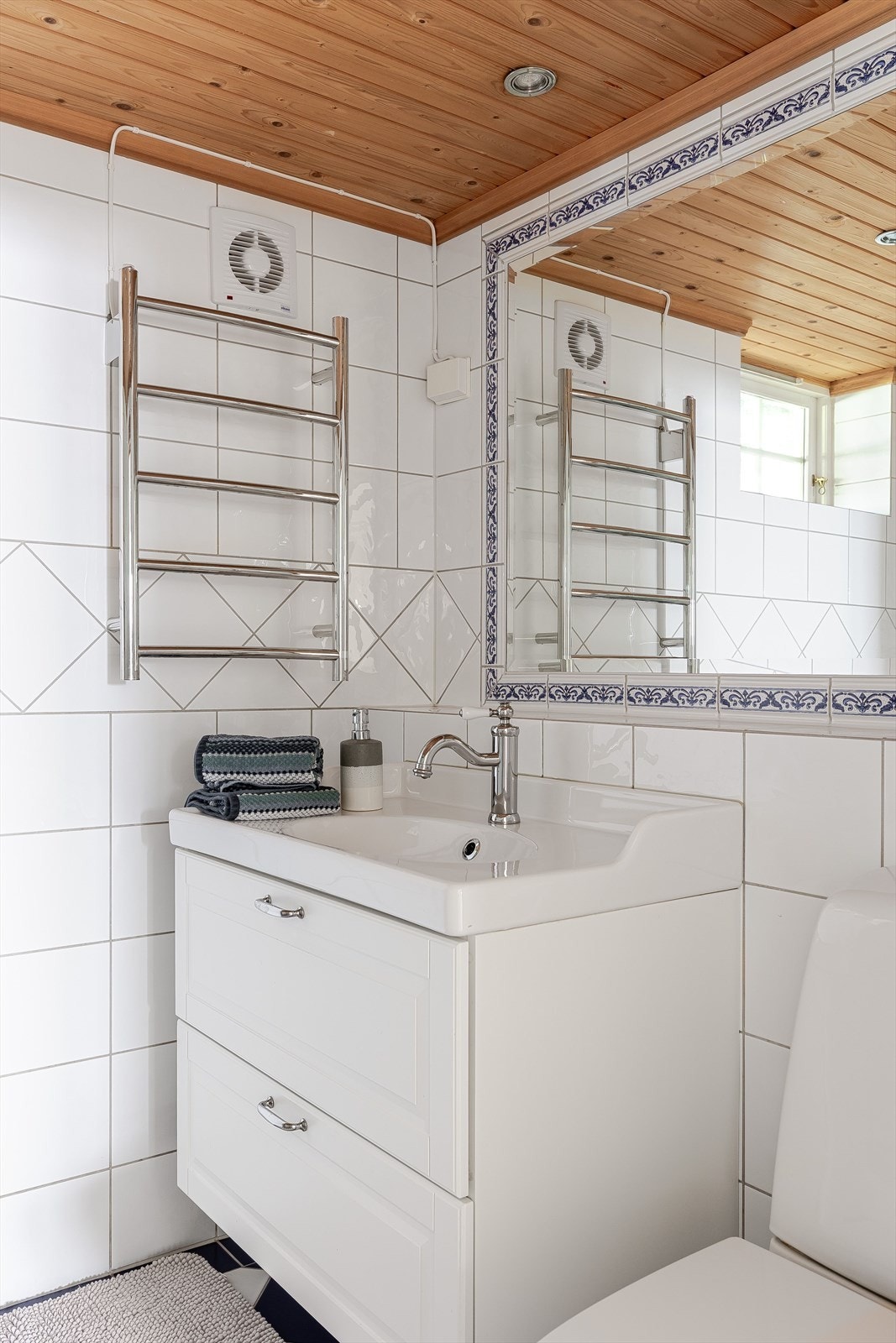 Lys og klassisk baderomsinnredning med skuffer og heldekkende servant, stort innmur speil over. Galleribilde