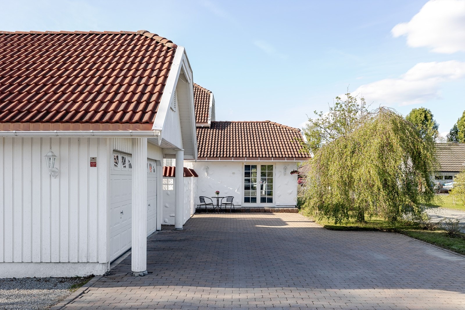 Gårdsplassen er pent opparbeidet med belegningsstein. Stor dobbeltgarasje på 45m² med elbil-lader og uinnredet loftsrom på ca. 35m² (ikke målverdig areal). Galleribilde