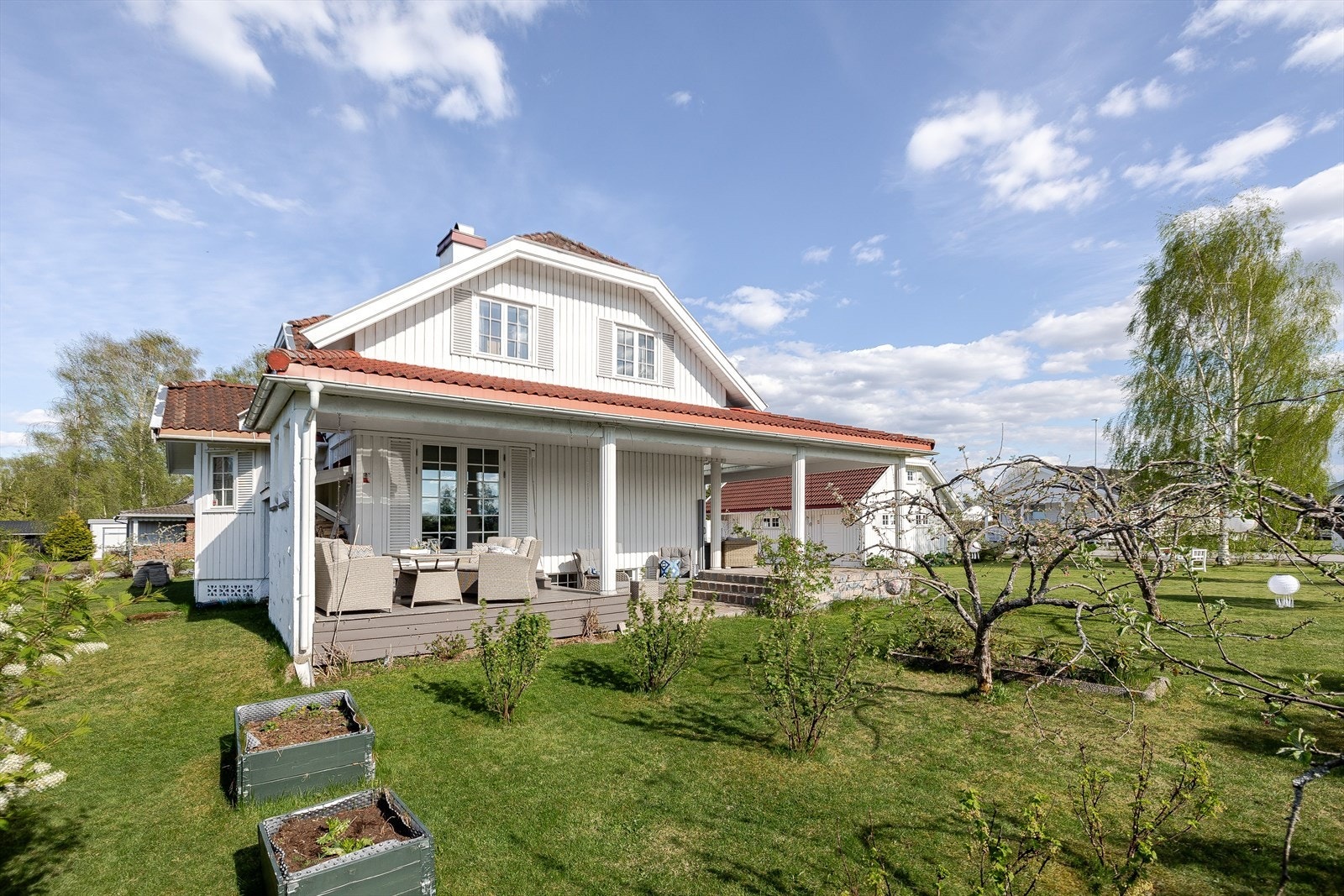 Utenfor terrassen er det en stor og pent opparbeidet hage med plantekasser, variert beplantning og flere frukt- og prydtrær. Galleribilde
