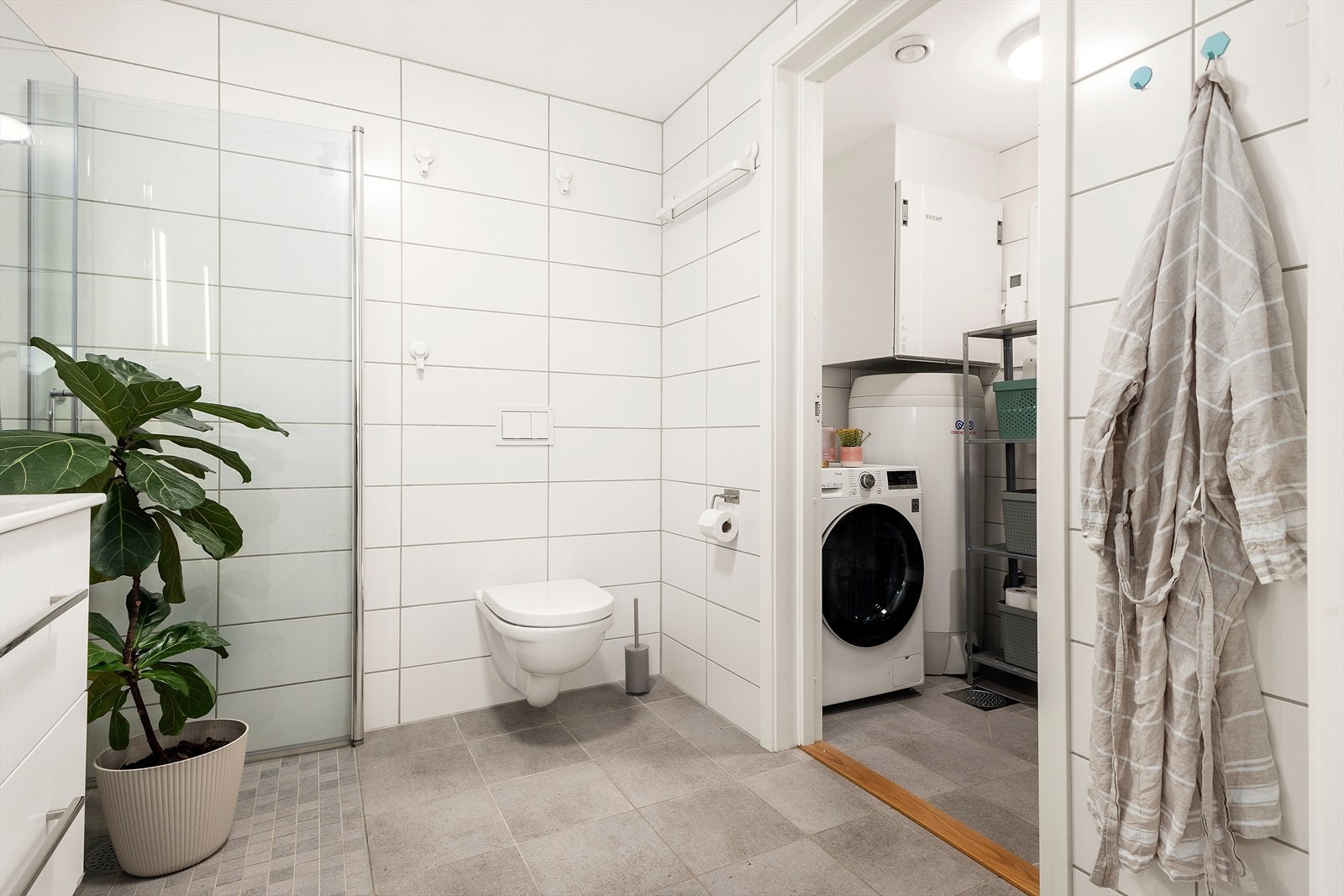 Vegg i vegg finner du vaskerommet praktisk plassert og innredet med opplegg for vaskemaskin, varmtvannsbereder og teknisk skap. Galleribilde