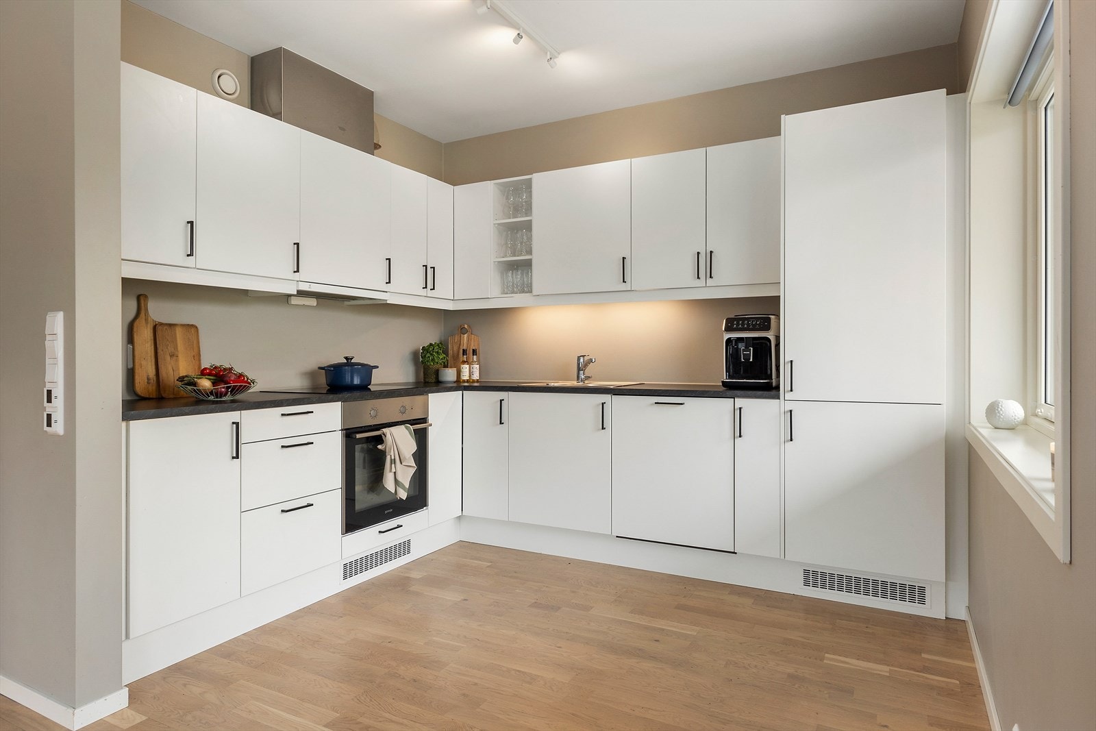 Kjøkkenet er godt utstyrt med slette, hvite fronter og en mørk laminert benkeplate. Galleribilde