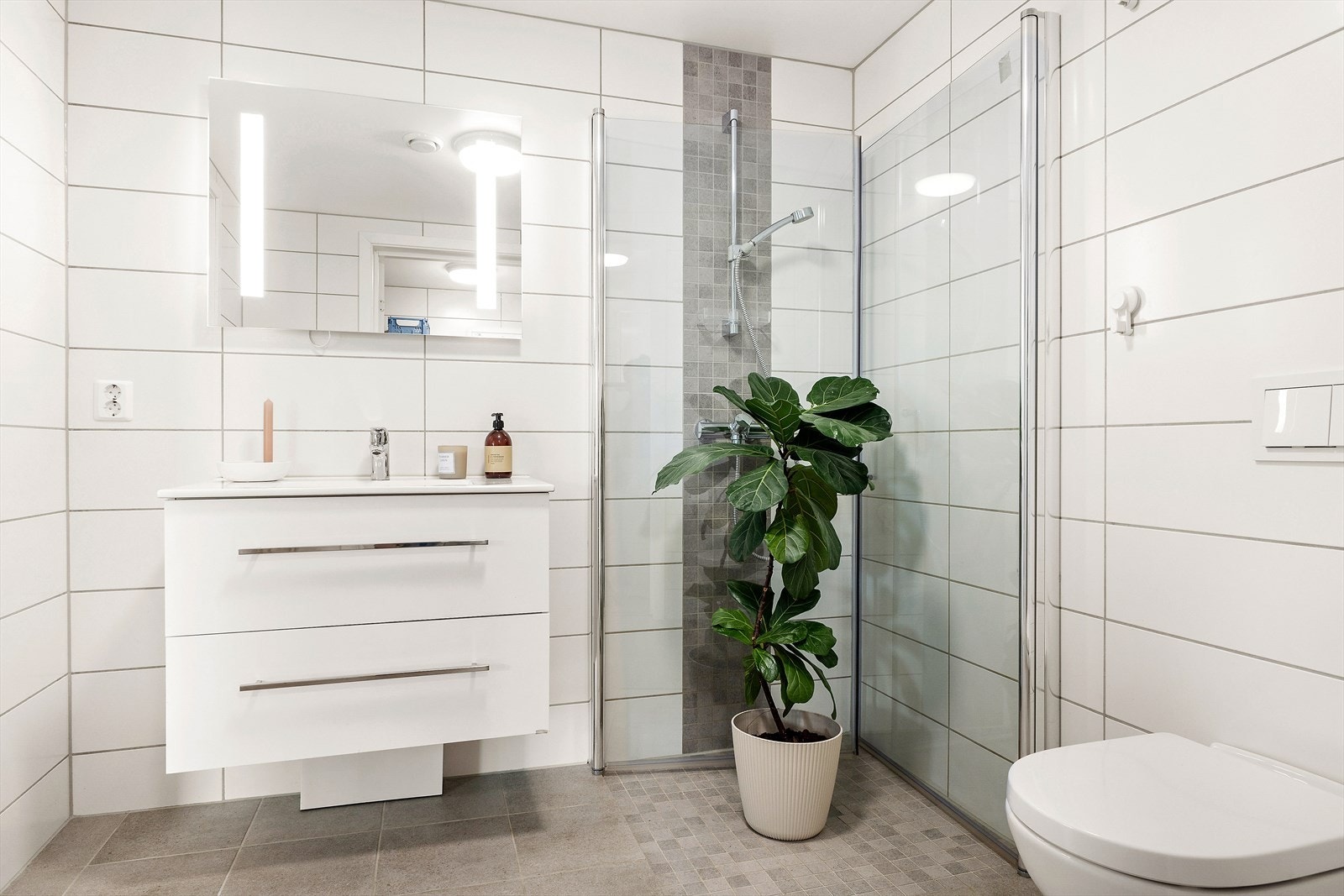 Plassbesparende dusj med dører som foldes mot vegg når det den ikke er i bruk. Galleribilde