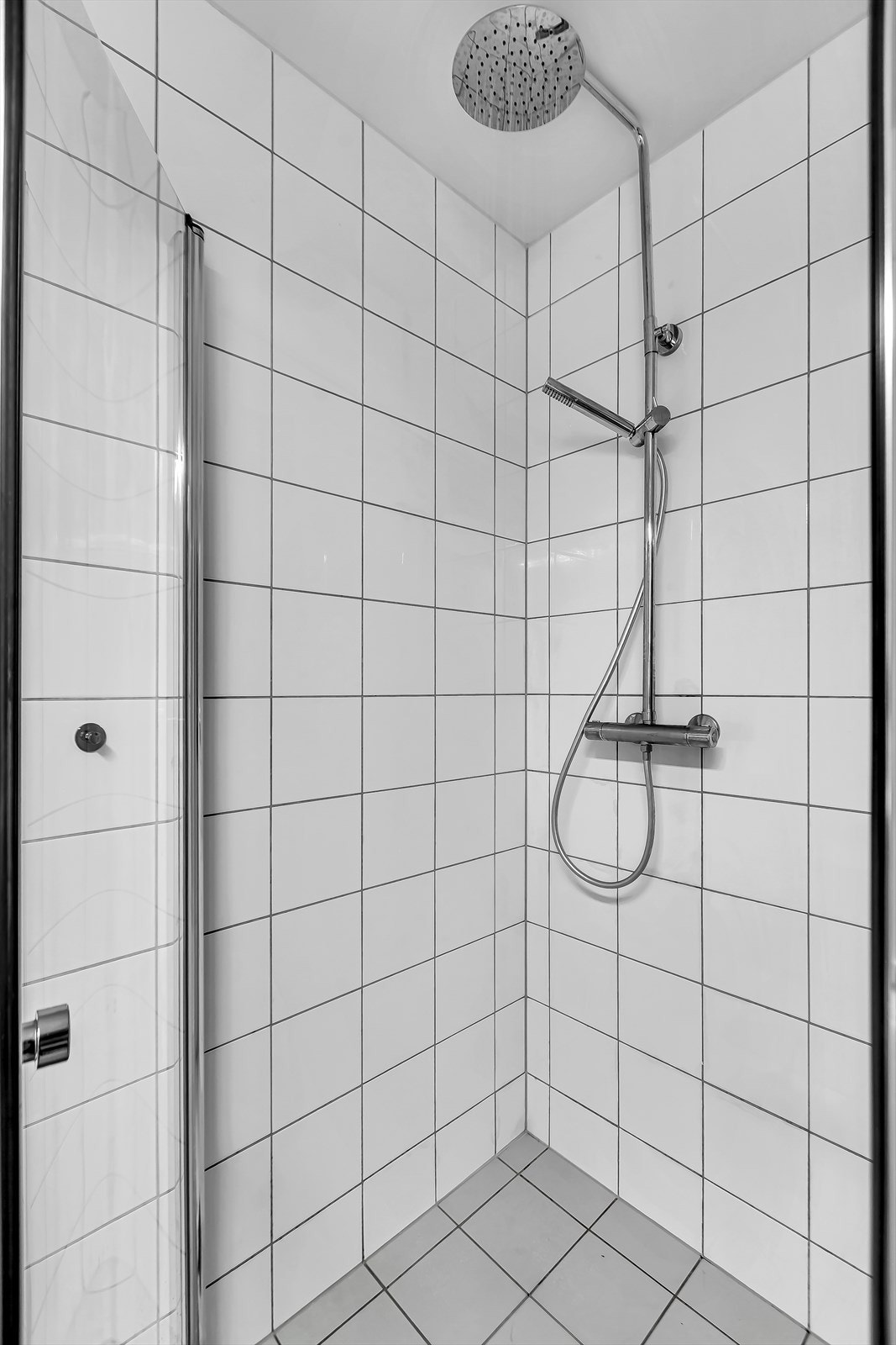 Badet har vegghengt toalet og dusjhjørne med dører i herdet glass. Galleribilde