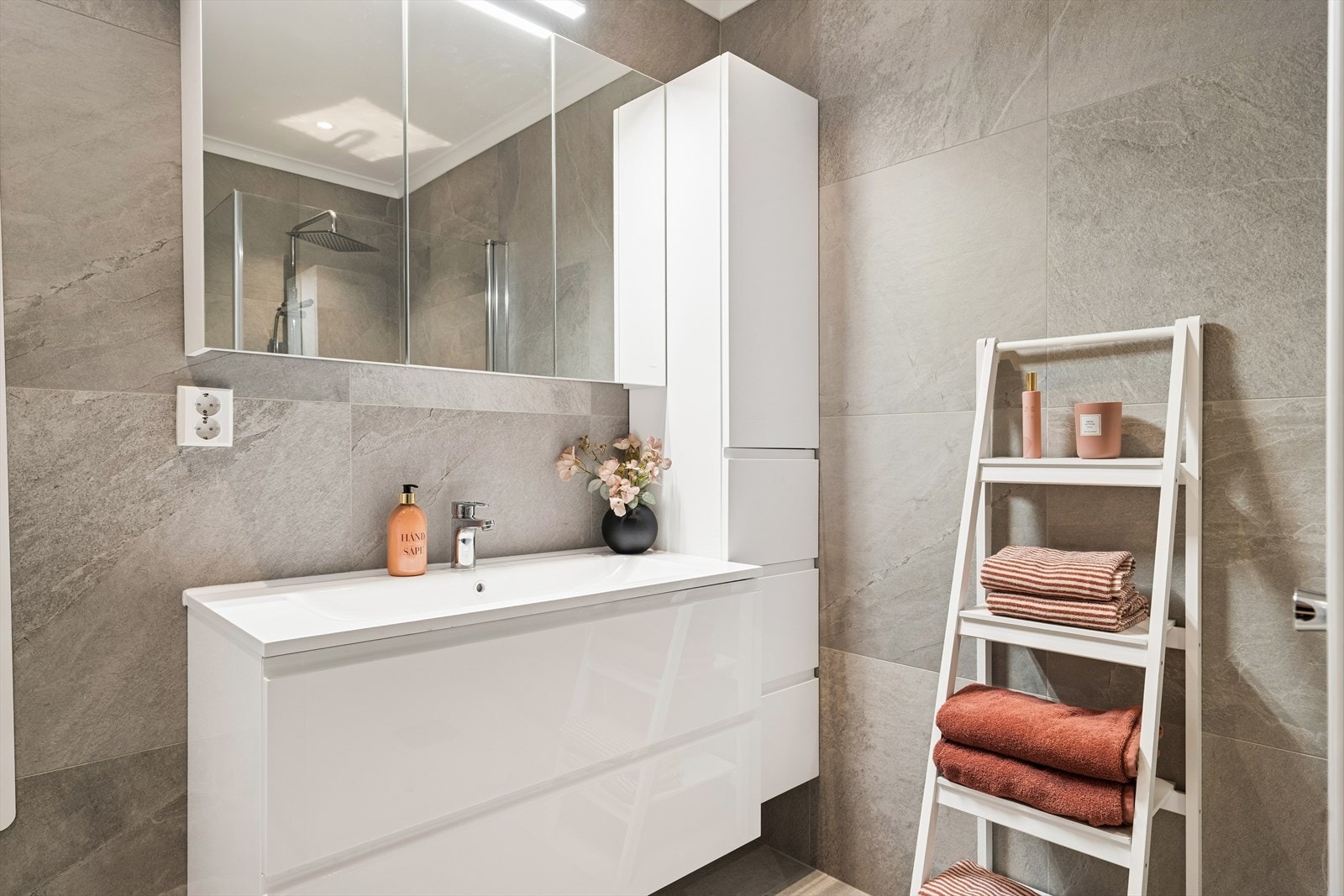 Rommet er utstyrt med servantskap med servant og armatur, vegghengt toalett med utenpåliggende sisterne, oppbevaringsskap og dusjvegger i glass. I en praktisk nisje er det opplegg for vaskemaskin. Galleribilde