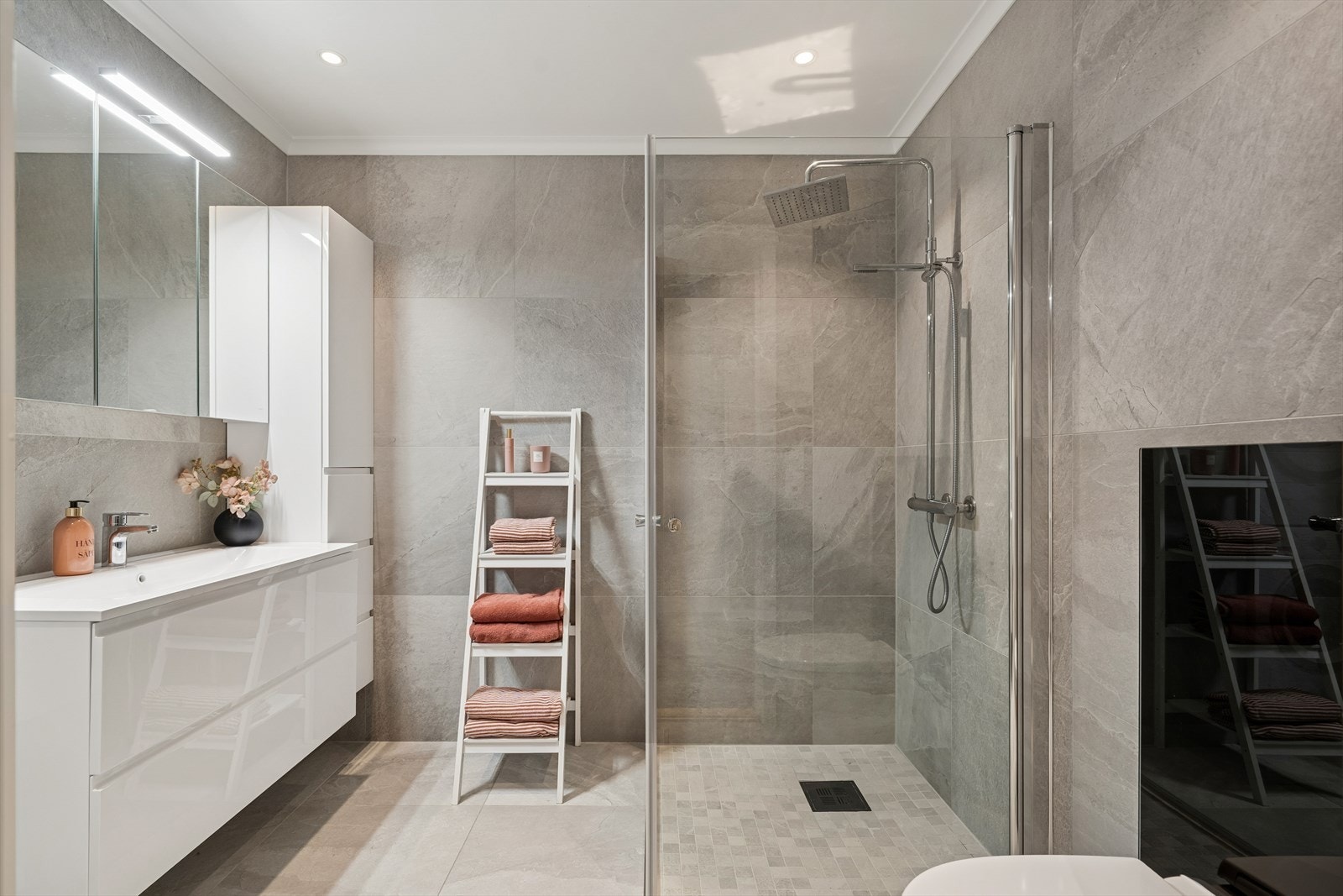 Badet fremstår moderne og gjennomtenkt med fliser på både gulv og vegger, samt sparklet og malt himling. Dusjsonen har nedsenket gulv for god vannføring. Galleribilde