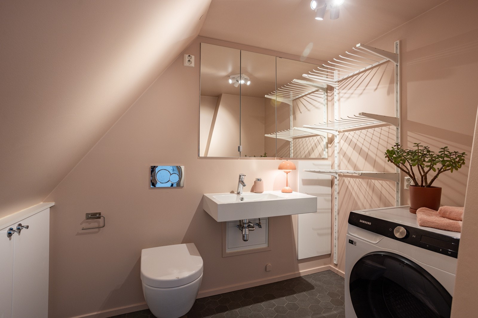 Det er baderom i begge etasjene. Bad på loft er utstyrt med servant, speilskap, vegghengt wc, integrerte veggskap og opplegg for vaskemaskin/tørketrommel. Galleribilde