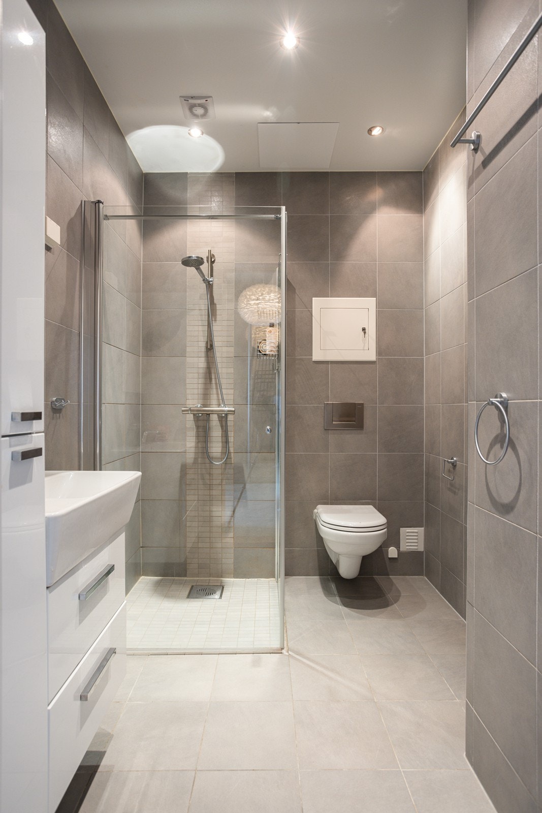 Badet i 3.etasje har dusj med innfellbare glassvegger, servantseksjon med skuffer, heldekkende porselensvask, speil med lys, høyskap og vegghengt wc. Galleribilde