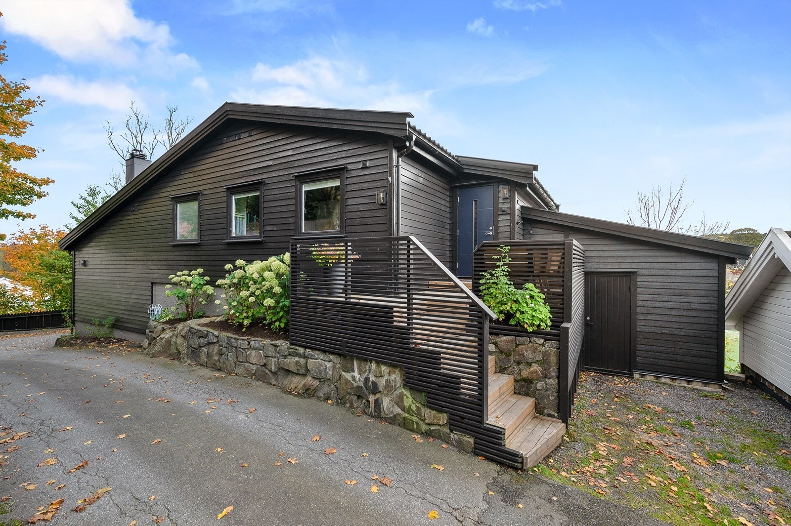 Inngangsparti med enkel trappeadkomst og beplantning som rammer inn inngangen på en harmonisk måte. Galleribilde