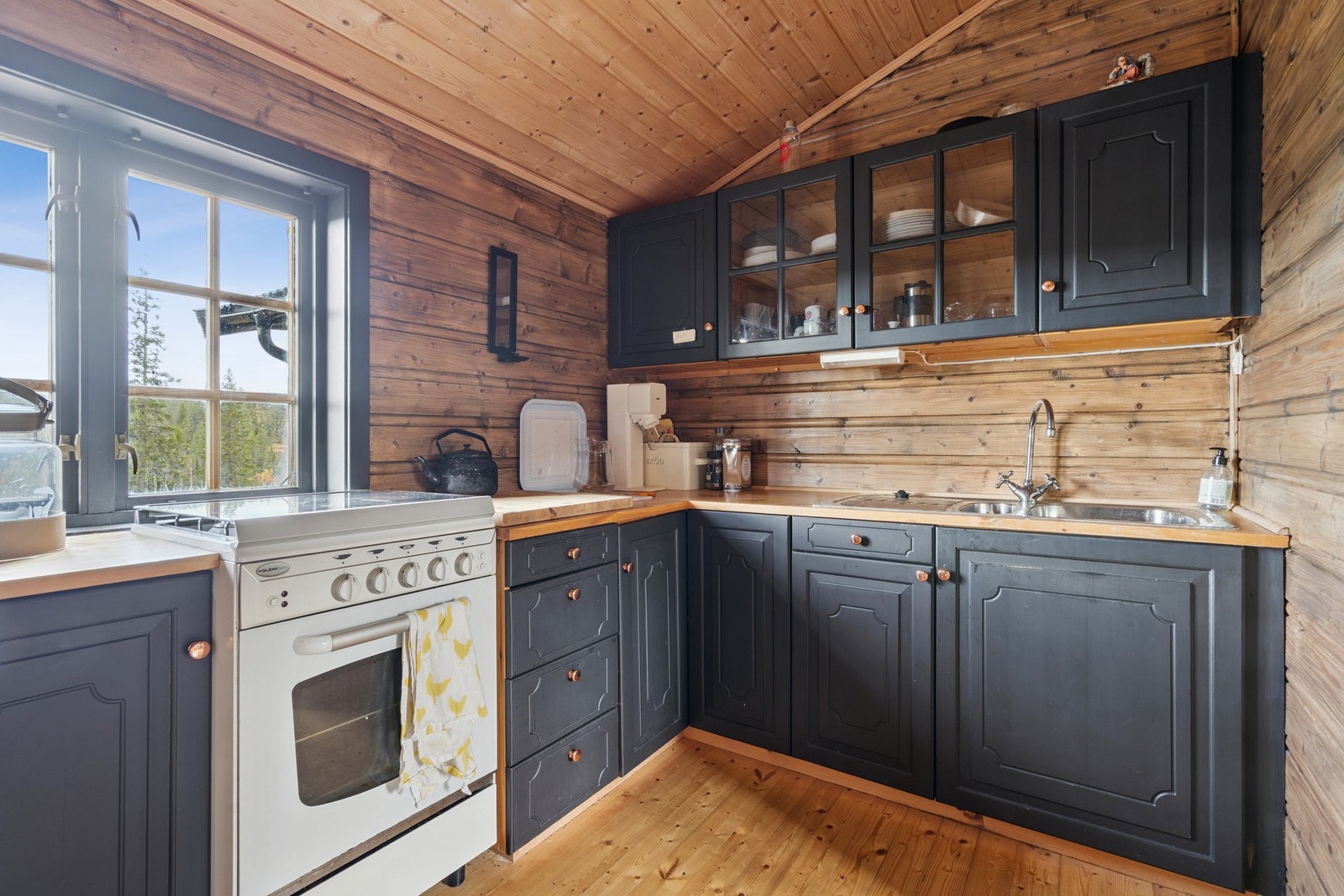 Kjøkken med behandlet tregulv, behandlet panel på vegger og ubehandlet panel i himling. Kjellerluke i gulv. Galleribilde