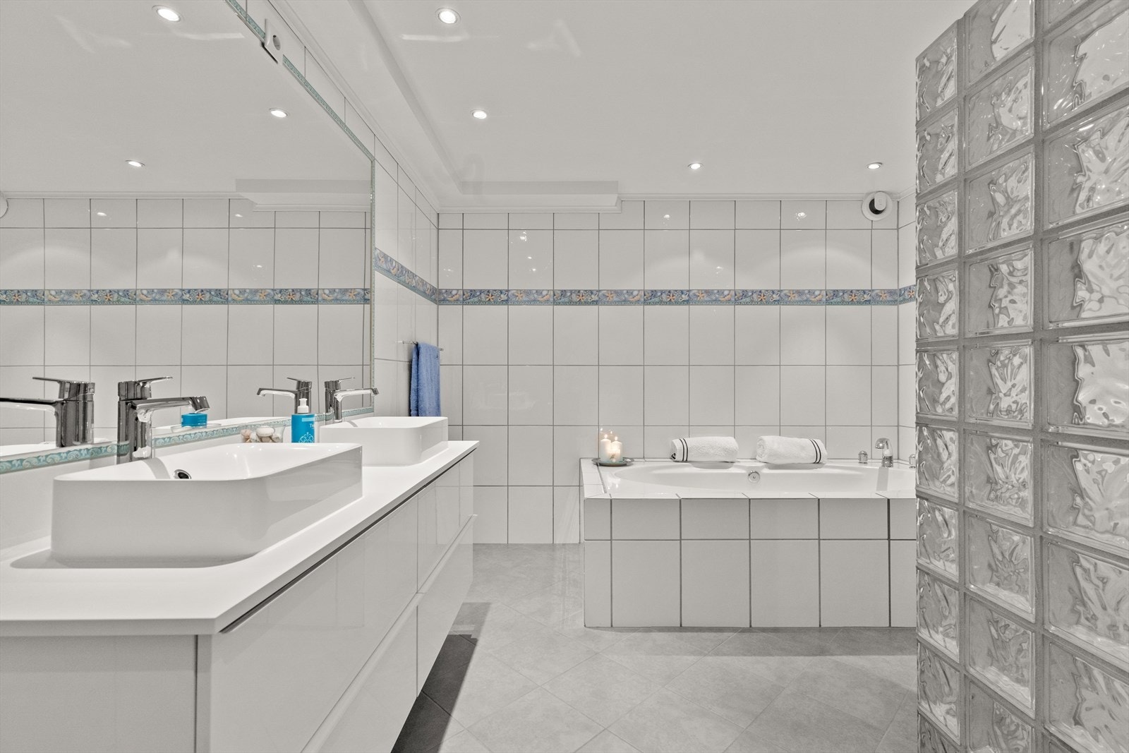 Leilighetens 1. bad har adkomst fra hovedsoverommet og gulvet er flislagt med flis på flis i 2022. Galleribilde