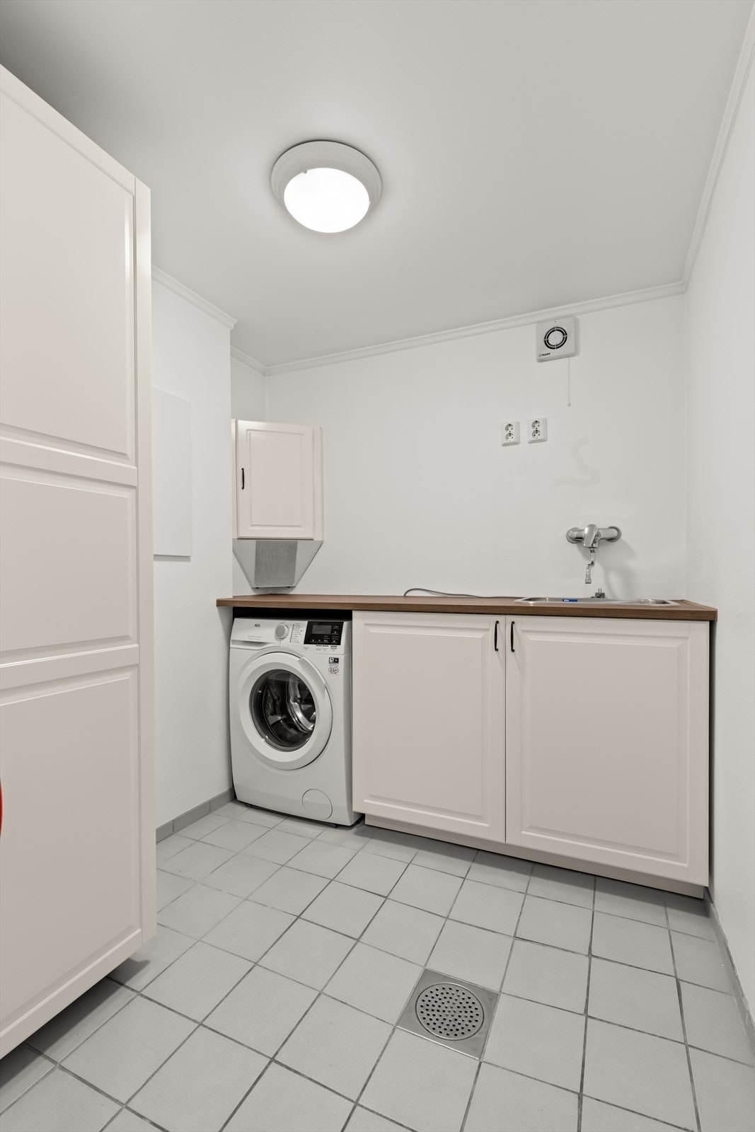 Praktisk vaskerom med flislagt gulv og malte vegger. Galleribilde