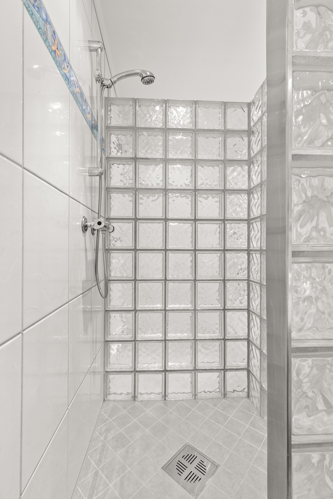 Dusjnisje med glassvegg og badekar med innebygget badekararmatur. Galleribilde