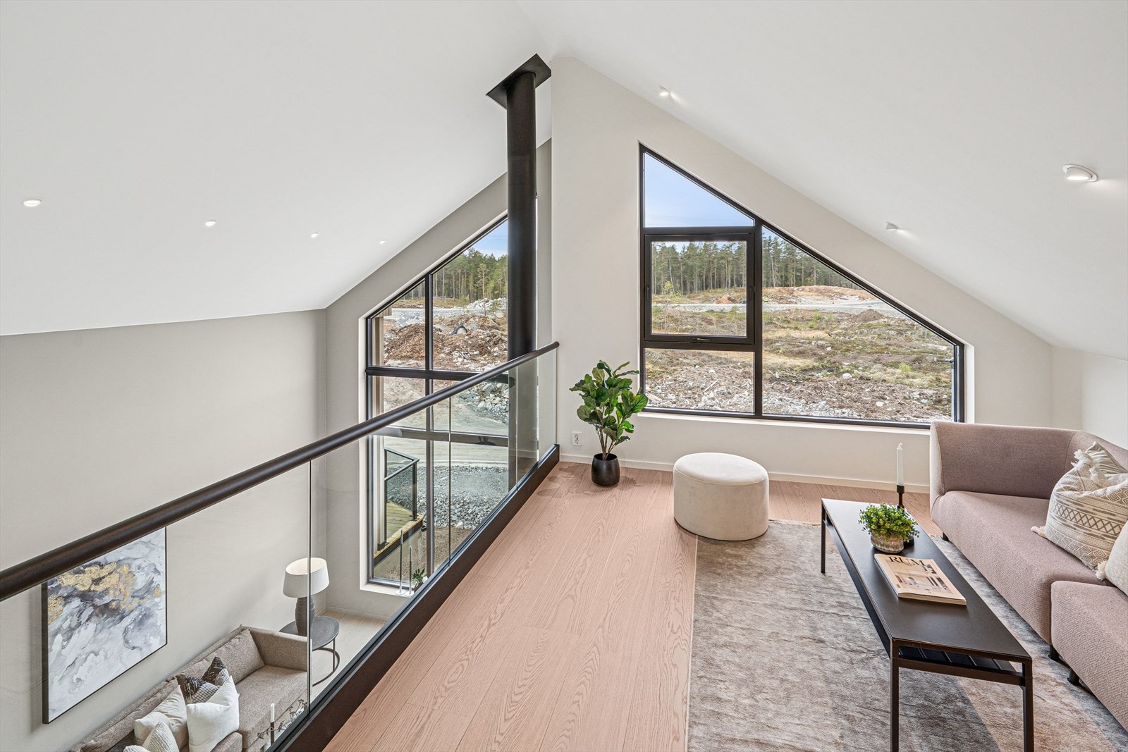 En praktisk stue med glassrekkverk med utsikt ned mot stuen i 2. etasje. Galleribilde