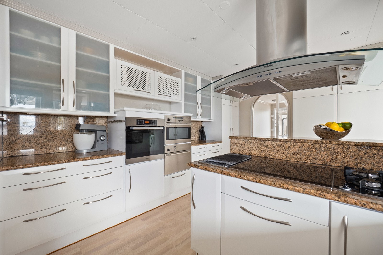 Kjøkkenet har integrerte hvitevarer. Kjøleskap, kjølehjørne, komfyr, dampovn, kaffemaskin og mikroovn, oppvaskmaskin og nedfelt platetopp Galleribilde