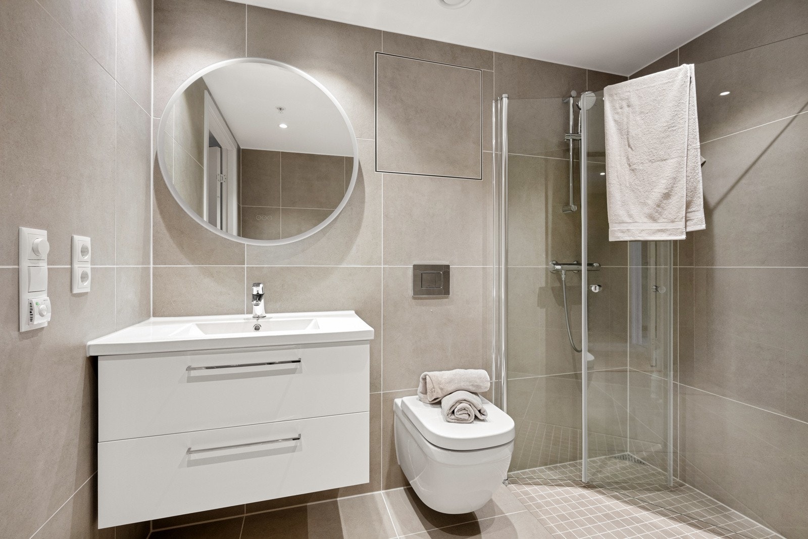 Varmekabler i gulvet sørger for en behagelig temperatur året rundt. Innredningen består av en heldekkende servant med to romslige underskuffer i hvit utførelse, som gir god oppbevaringsplass til det du trenger i hverdagen. Galleribilde