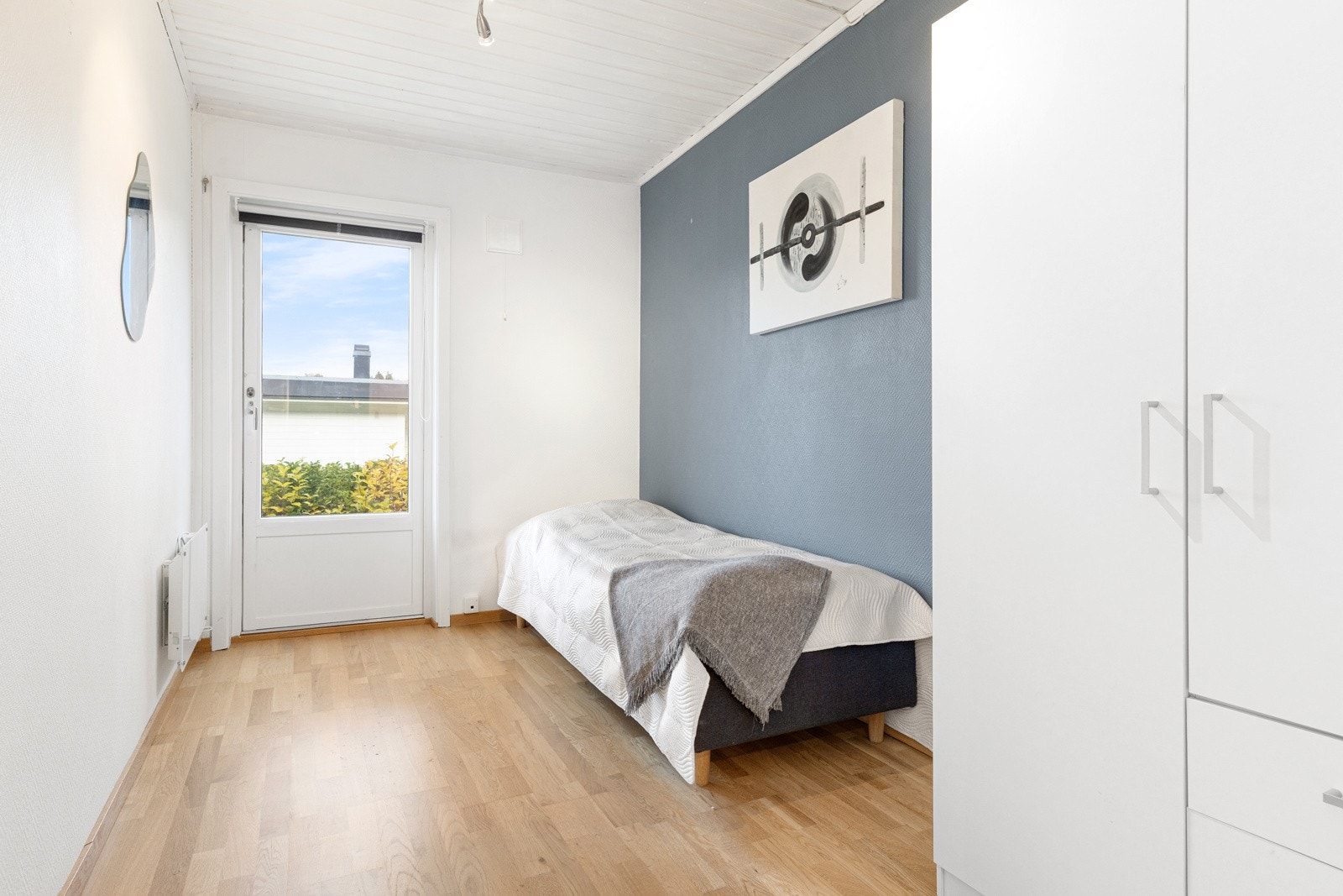 Lyst soverom med plass til seng og garderobe. Nøytrale farger og laminat på gulv. Utgang til hage. Galleribilde