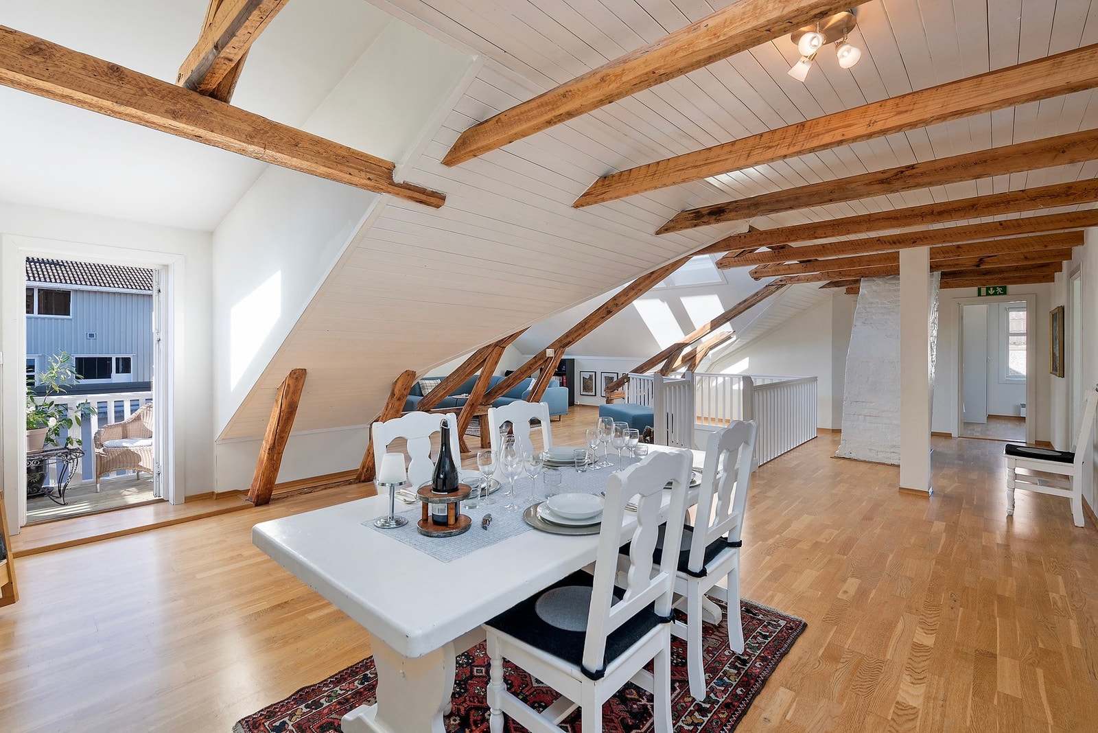 En lys og romslig leilighet med skråtak og bjelker av tre som gir en urban og klassisk helhetsfølelse Galleribilde