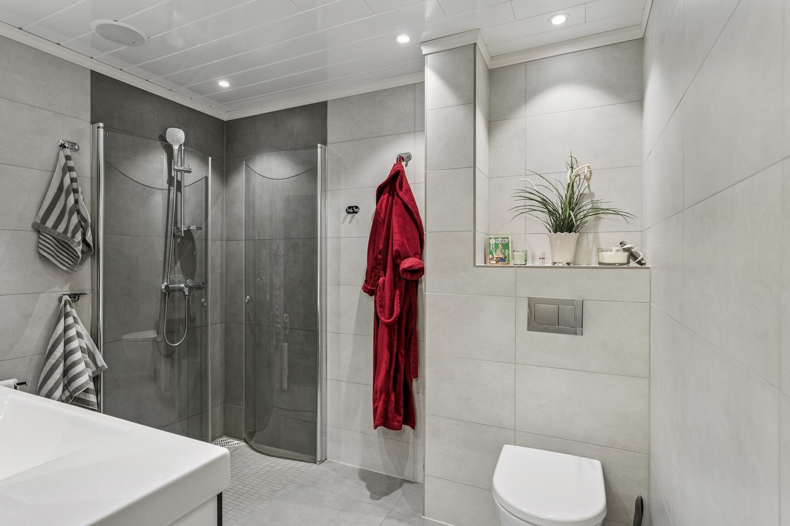 Rommet er utstyrt med vegghengt toalett og dusjhjørne med innfellbare glassdører. Galleribilde