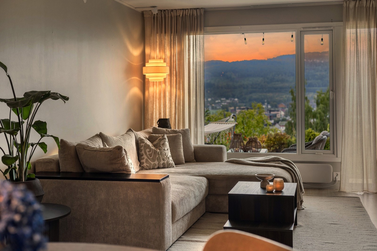 Lun og innbydende sofakrok med store vinduer som åpner opp mot hagen og utsikten. Galleribilde