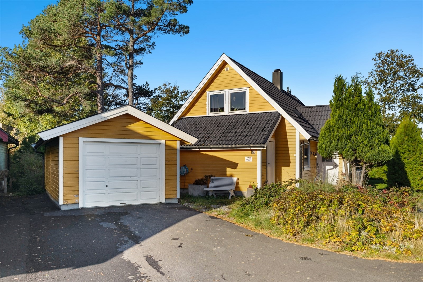 Tomten er opparbeidet med bl.a. plen, diverse prydbuser, asfaltert innkjørsel og garasje. Galleribilde