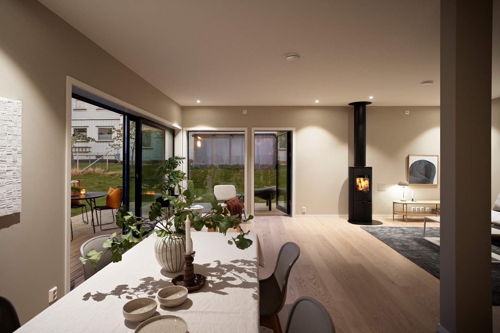 Åpent & sosialt allrom med kjøkken og stue, store vindusflater og peis. Galleribilde