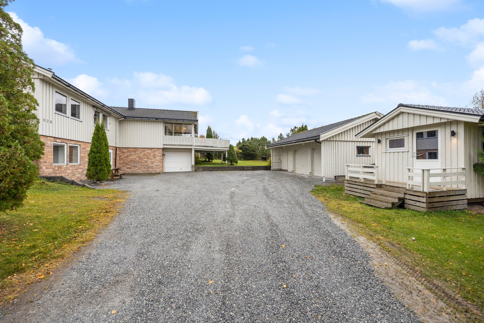 Pent opparbeidet med gruslagt gårdsplass og steinmur mot plenlagt areal Galleribilde