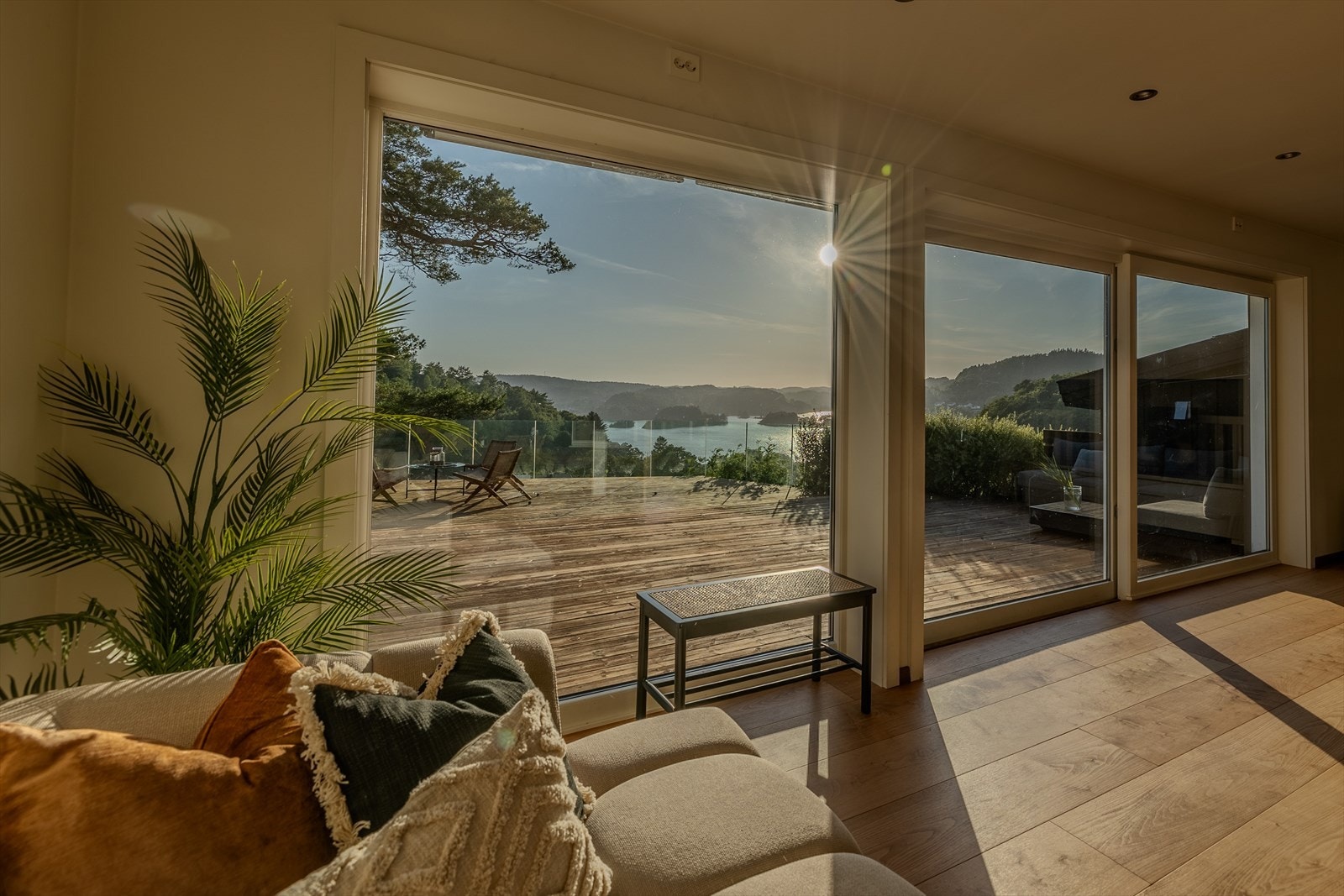 Flott utsikt gjennom store panoramavinduer på to av stuens vegger. Skyvedør ut til terrassen Galleribilde