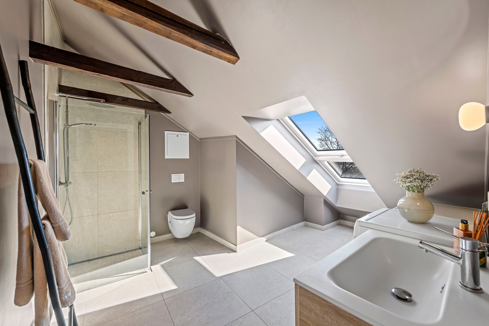 Badet har store, lyse fliser fra Bella på gulvet og i dusjsonen. Dusjen har regnfallsdusj, hånddusj og innfellbare glassdører. Galleribilde