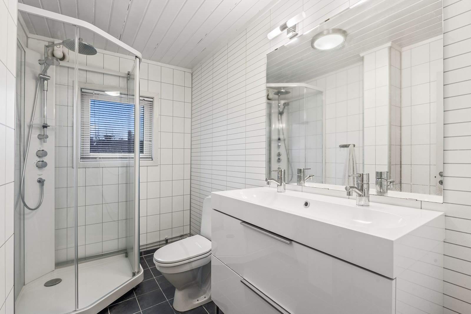 Stilrent bad med flislagt gulv med gulvvarme og baderomsplater på veggene Galleribilde